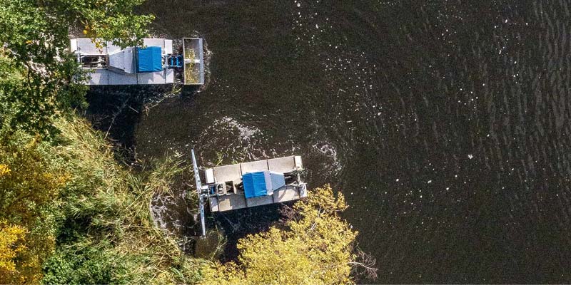 Aerial View of Two Aquatic Weed Harvester Boats With Blue Canopies Working