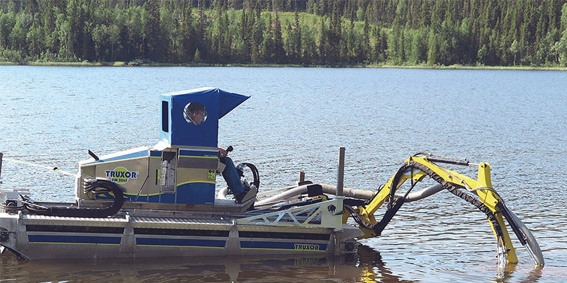 Truxor amphibious weed harvester working in open water with hydraulic arm extended