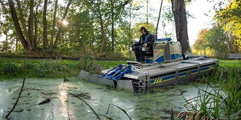 Truxor operator managing dense algae and aquatic weeds in a narrow marsh channel