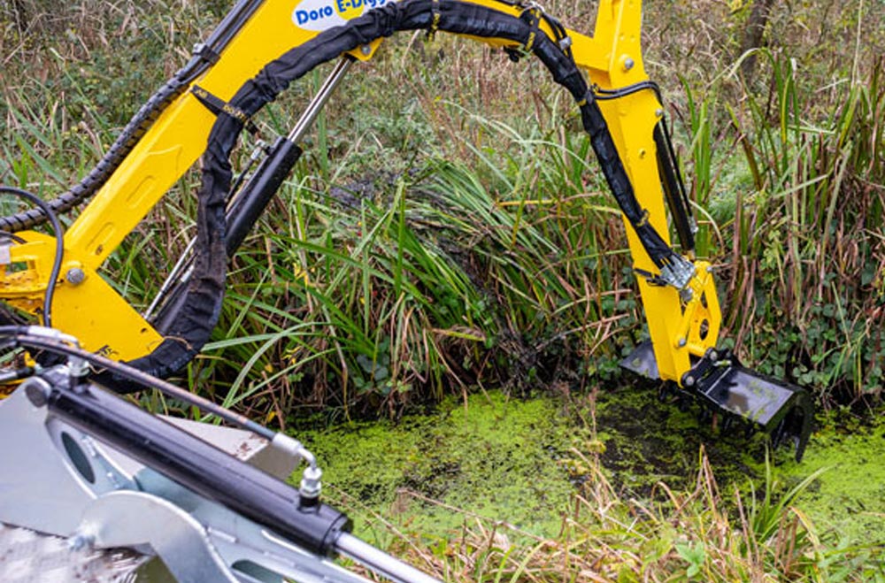 Truxor dredger removing dense aquatic vegetation in shallow water
