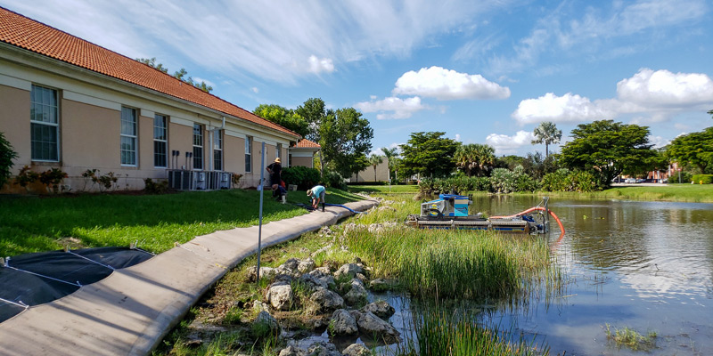 Truxor machine dredging a pond near a building