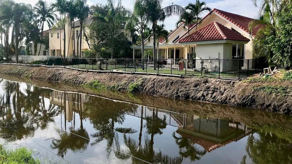 a canal behind Florida homes with muddy shoreline before maintenance